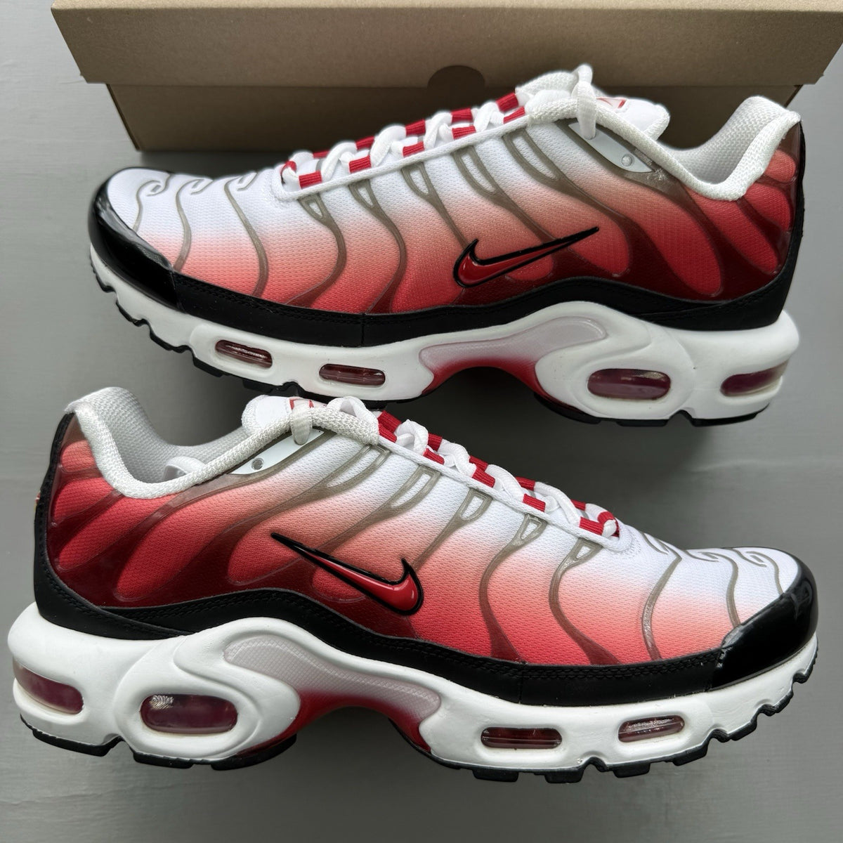 Nike Air Max Plus TN white trainers with black and university red accents, mesh material.