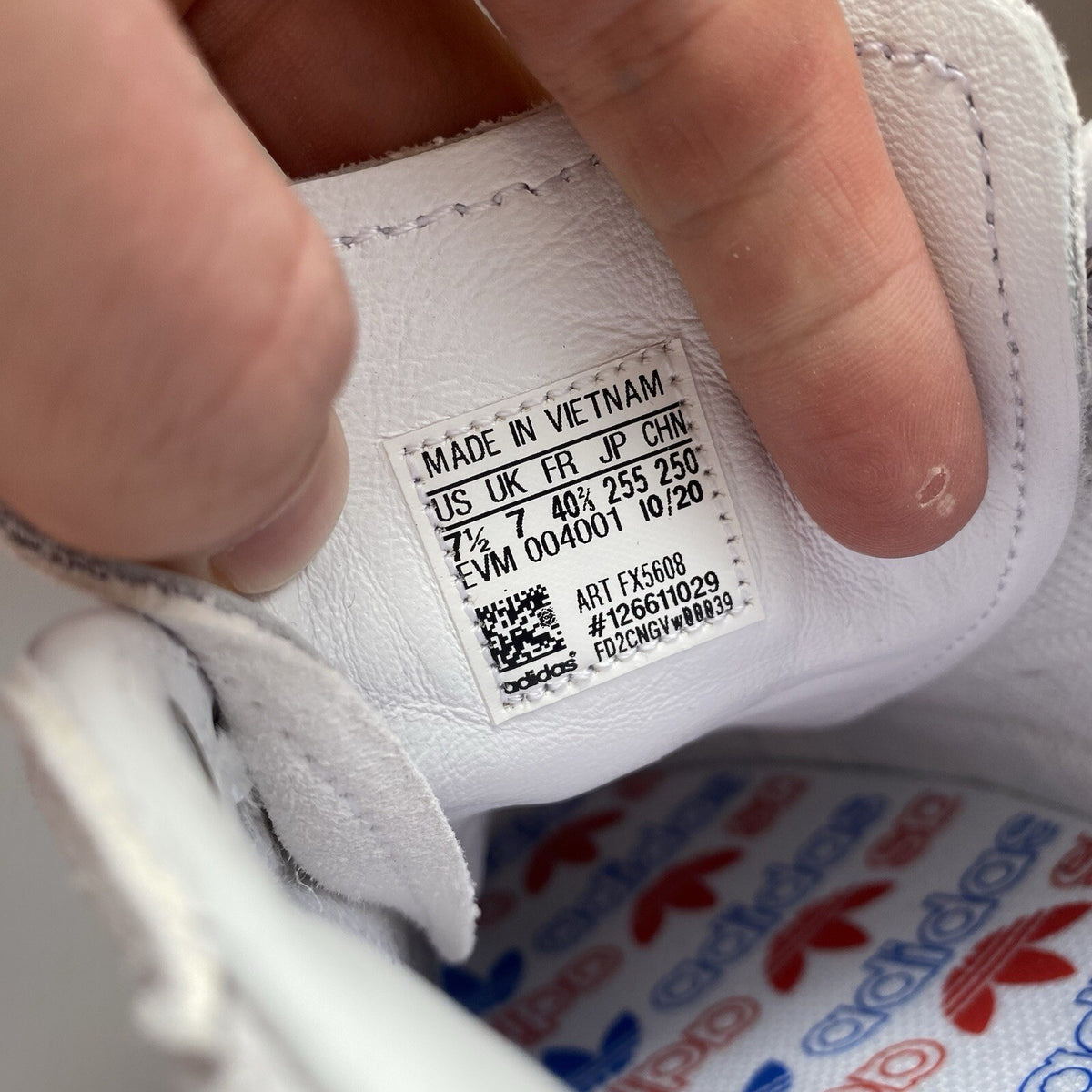 Adidas white trainers with blue and beige accents, featuring classic logo detail.
