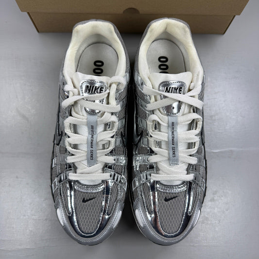 Nike athletic shoes metallic silver with mesh upper and reflective detailing.