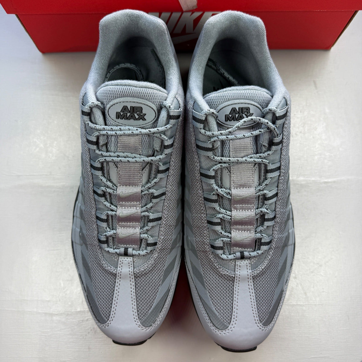 Nike Air Max 95 grey trainers with caution strip detailing and black accents.