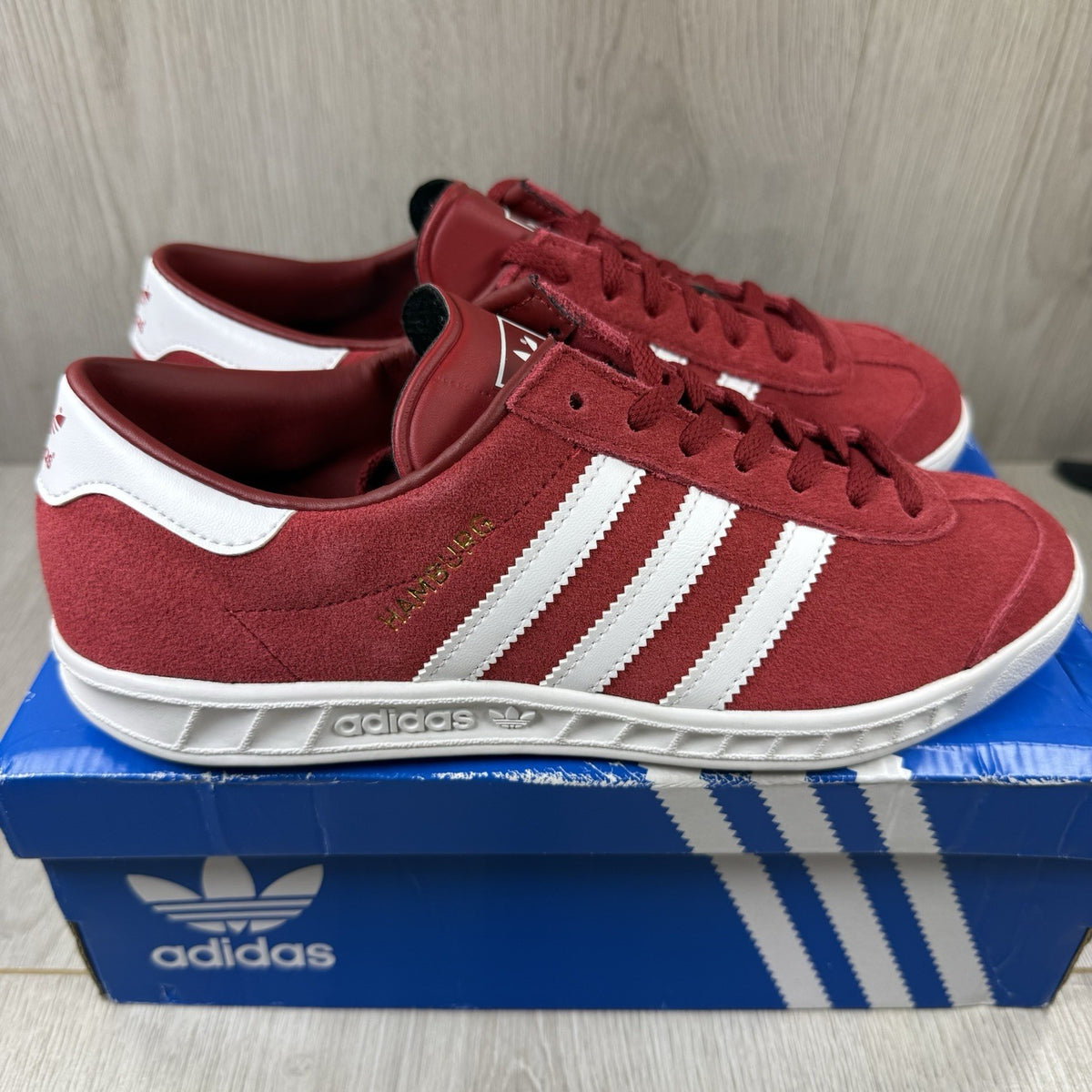 Adidas red trainers with white stripes and logo, classic suede material.