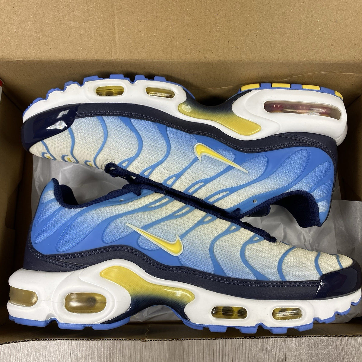 Nike Air Max Plus TN blue trainers with yellow accents and signature swoosh logo.