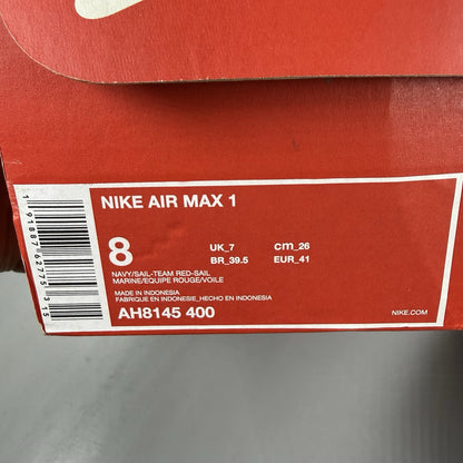 Nike Air Max 1 red trainers with navy accents and gum sole, featuring logo details.