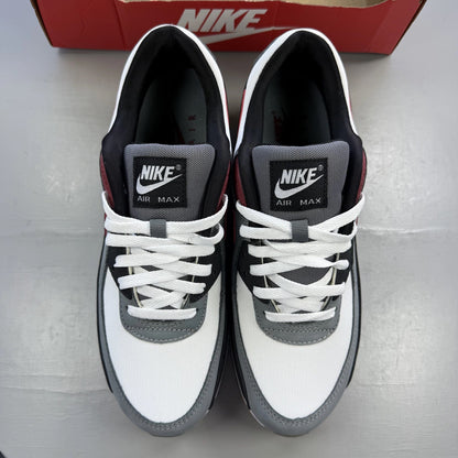 Nike Air Max 90 grey trainers with red accents and gum sole, featuring logo details.