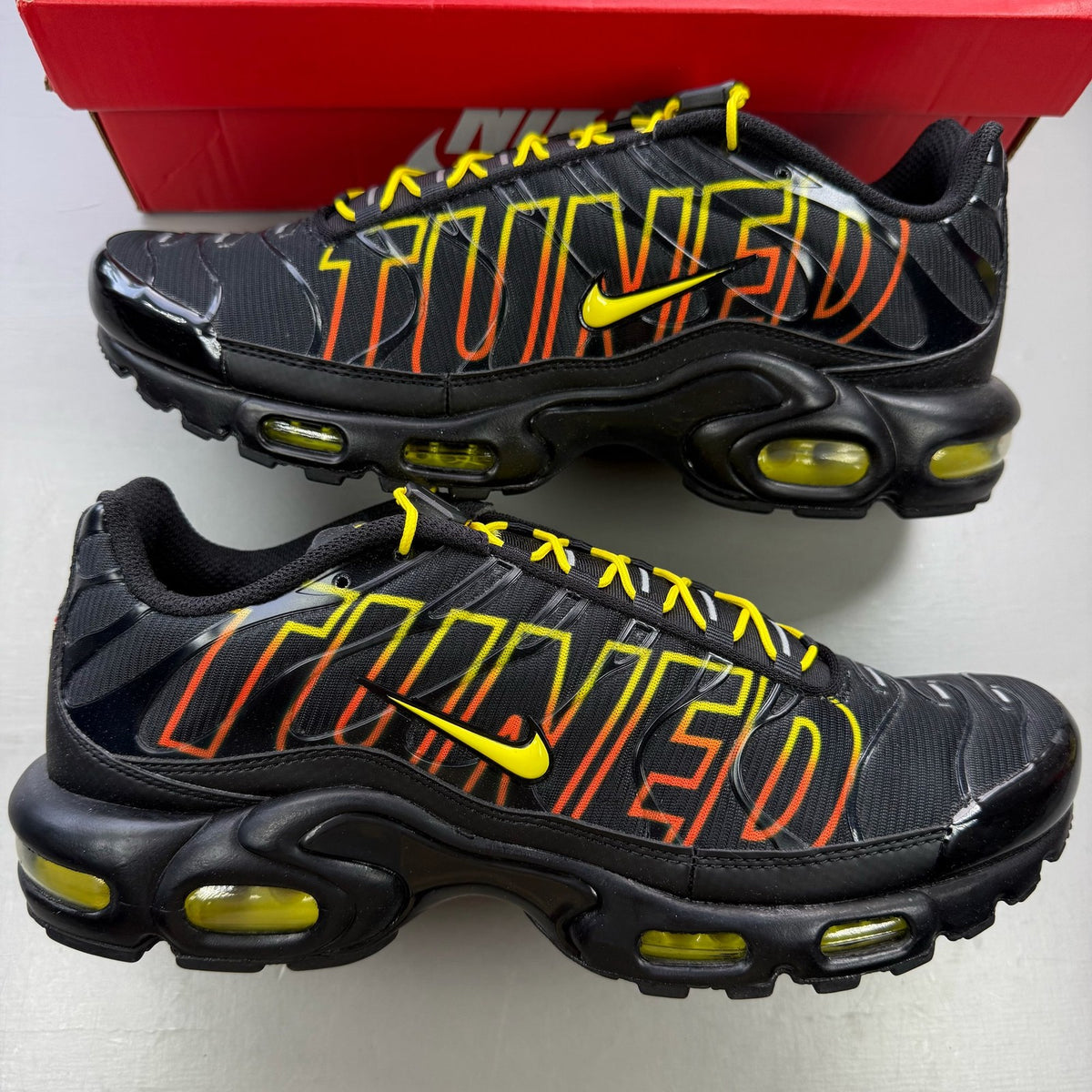 Nike black trainers with Tuned Air technology and sunrise pattern accents.