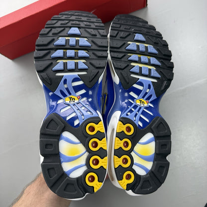 Nike Air Max Plus TN white trainers with blue and yellow accents, featuring logo detailing.
