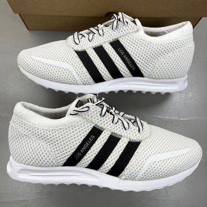 Adidas white trainers with black accents and iconic three stripes design.