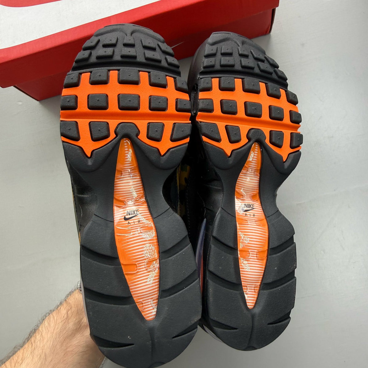 Nike Air Max 95 black trainers with orange camo accents and logo details.