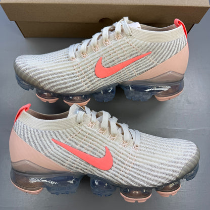 Nike trainers light cream pink Flyknit material with Air cushioning and logo details.