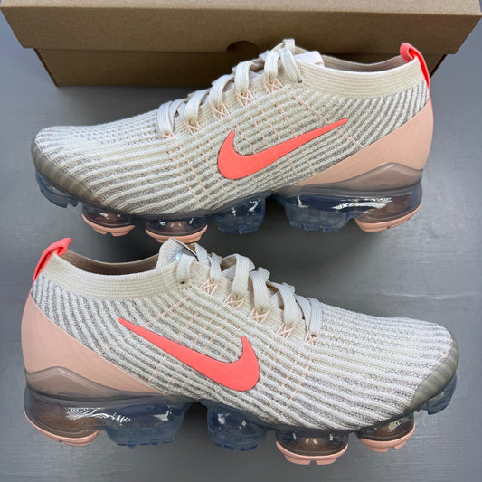 Nike trainers light cream pink Flyknit material with Air cushioning and logo details.