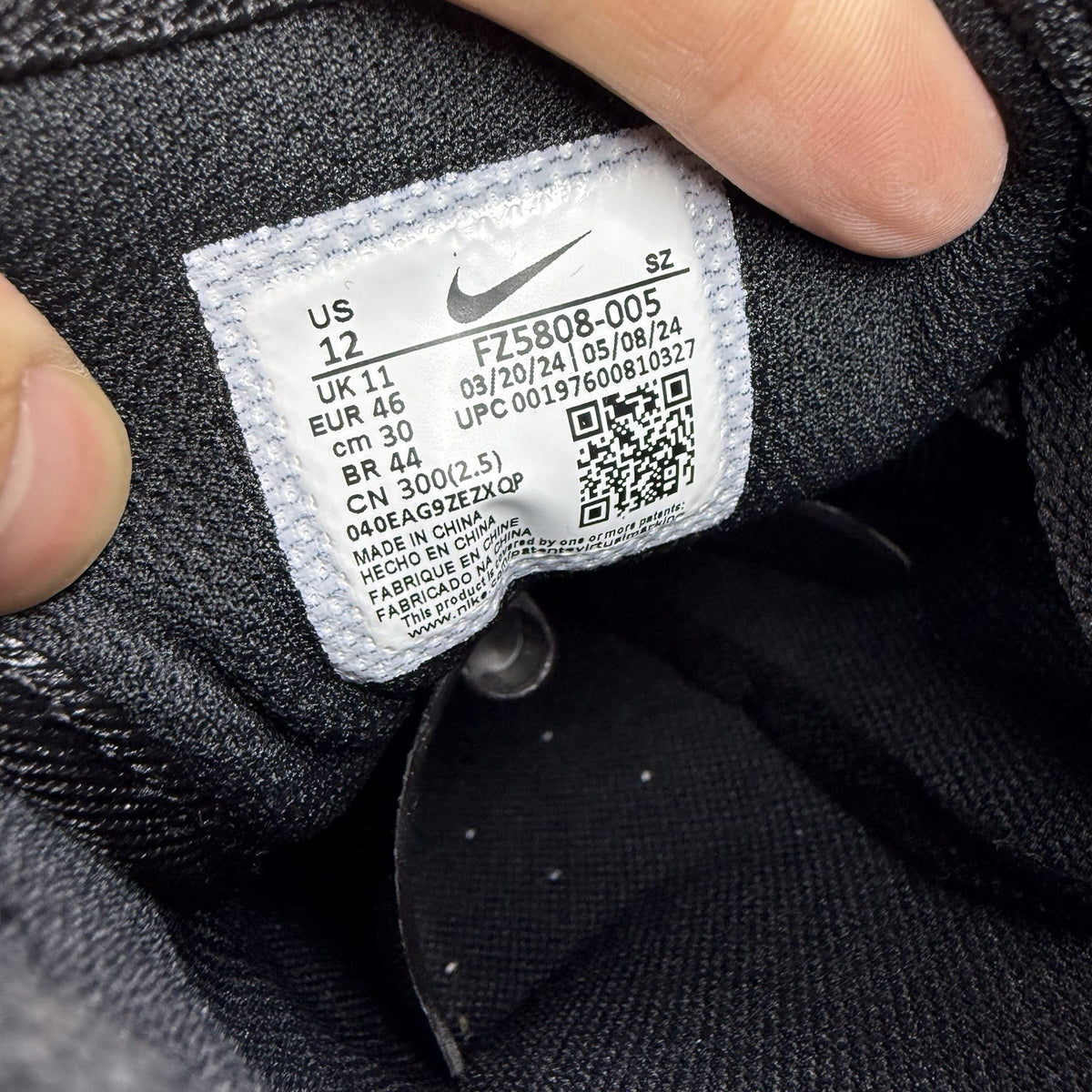 Nike Air Max 1 Essential black trainers with yellow accents and logo detail.