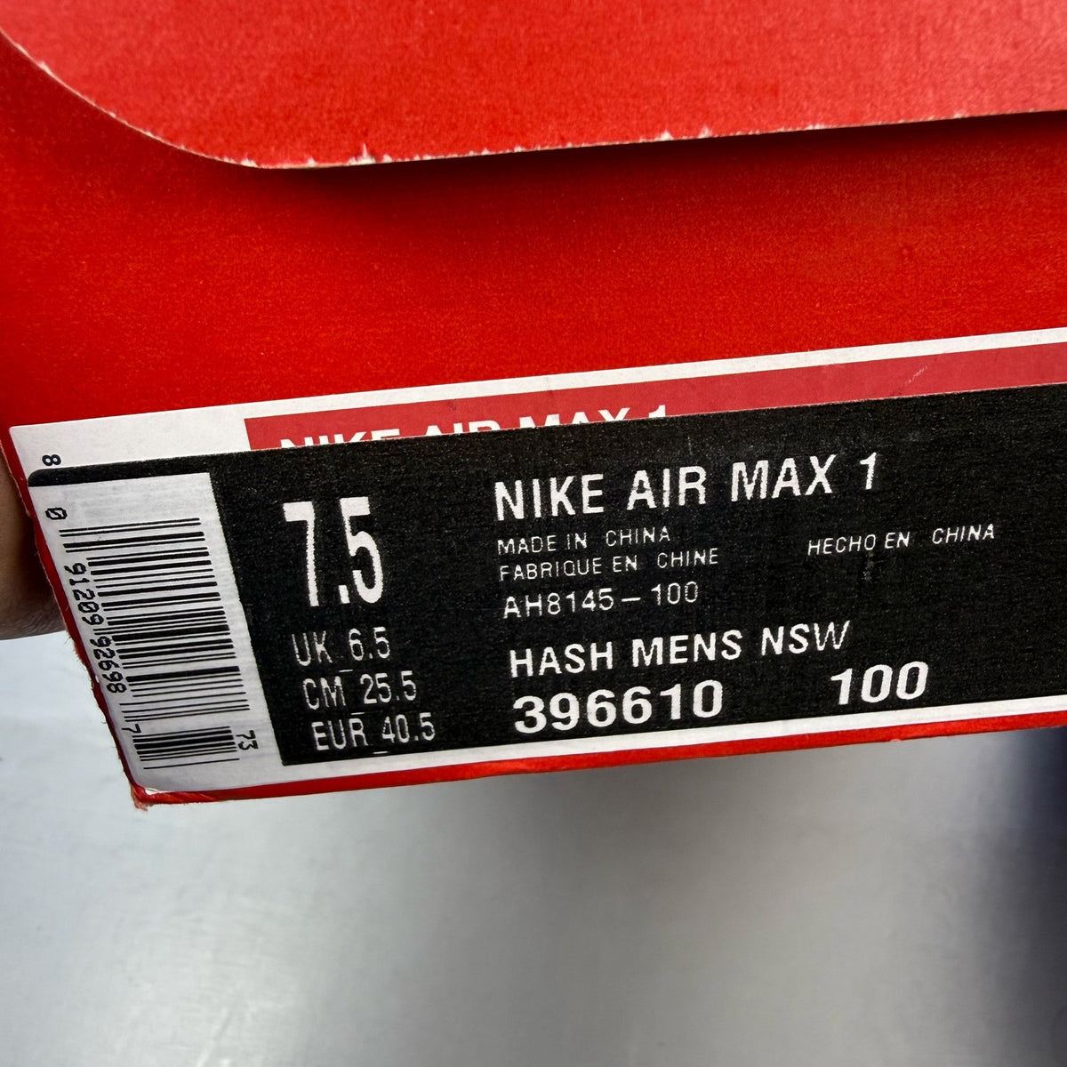 Nike Air Max 1 trainers grey red white with logo and mesh material details.