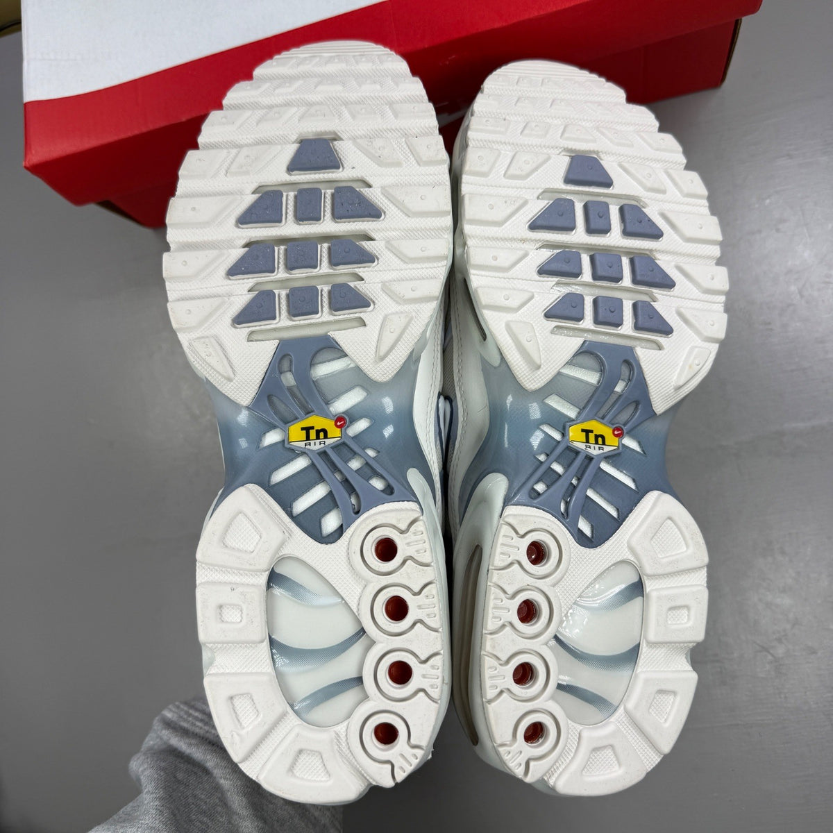 Nike white athletic shoes with Air Max Plus TN design and visible logo details.