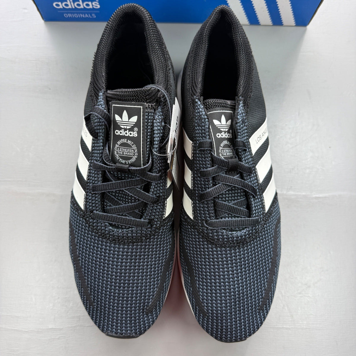 Adidas black deck shoes with white stripes and logo, brand new in box.