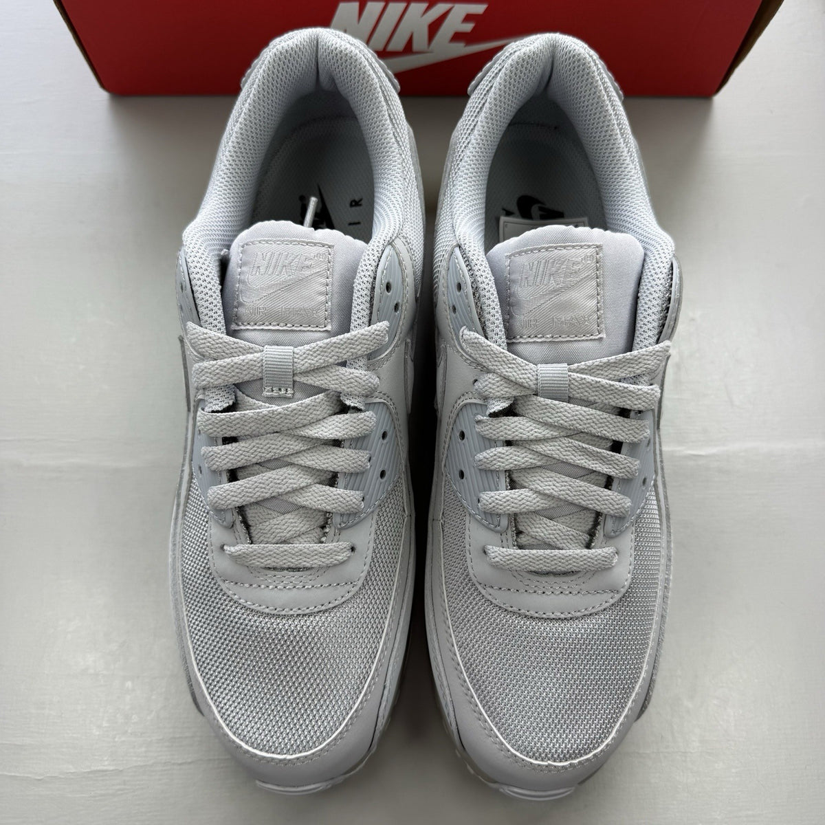 Nike Air Max 90 Recraft grey trainers with iconic swoosh logo and mesh detailing.