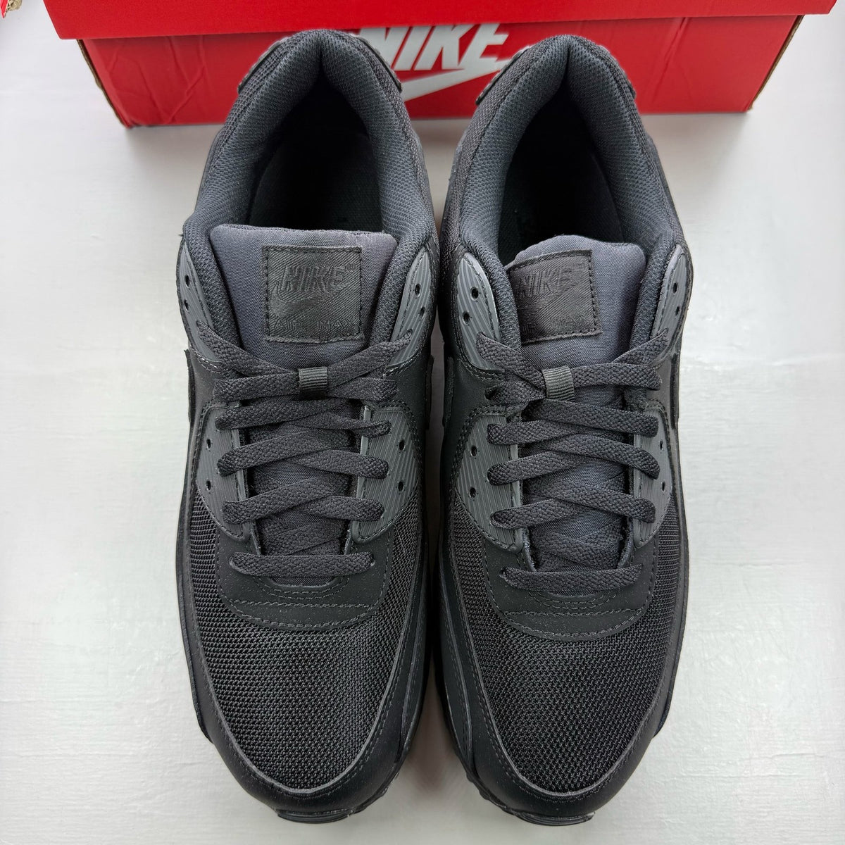 Nike Air Max 90 trainers black with logo detailing and sleek design.