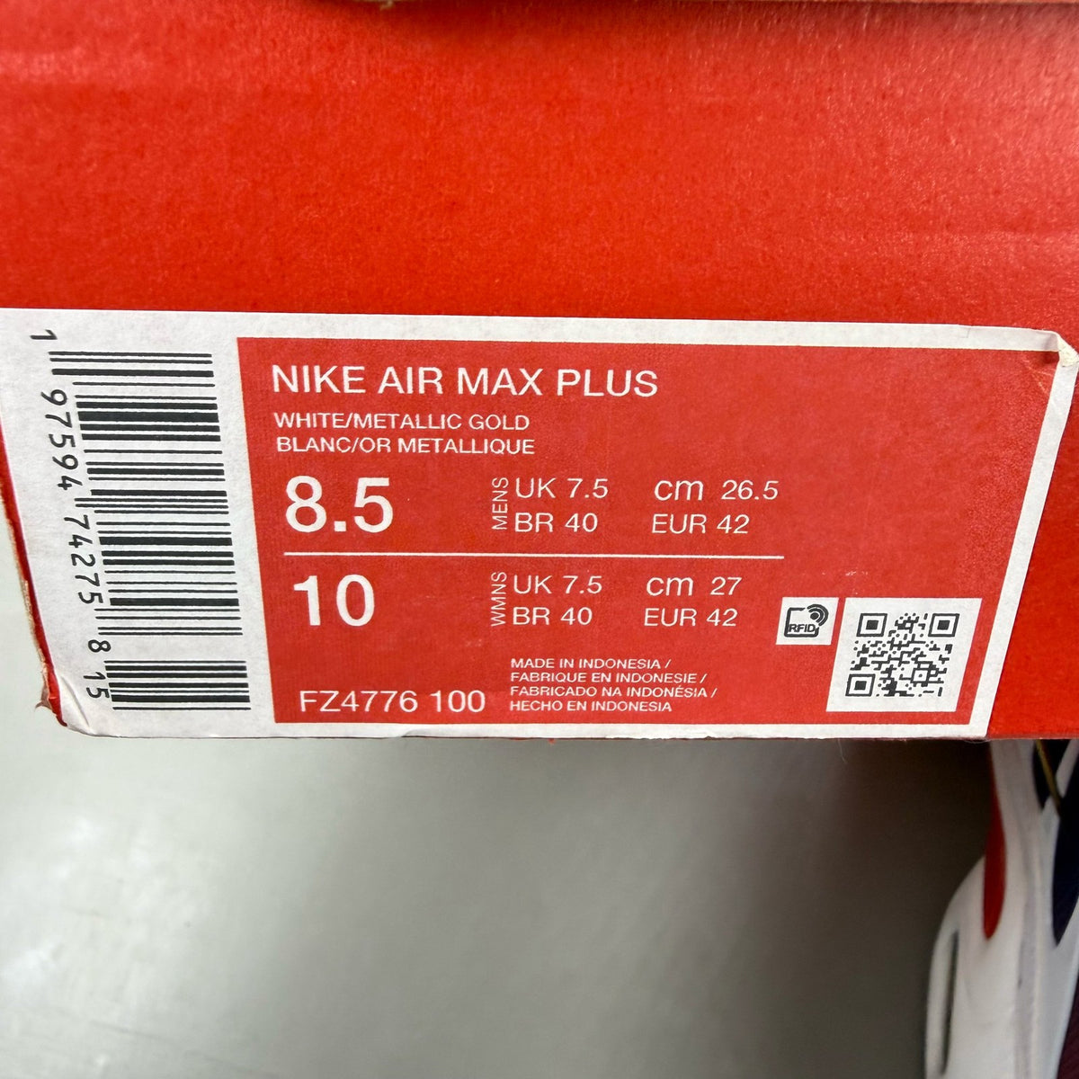 Nike Air Max Plus trainers white with navy and red accents, featuring logo details.