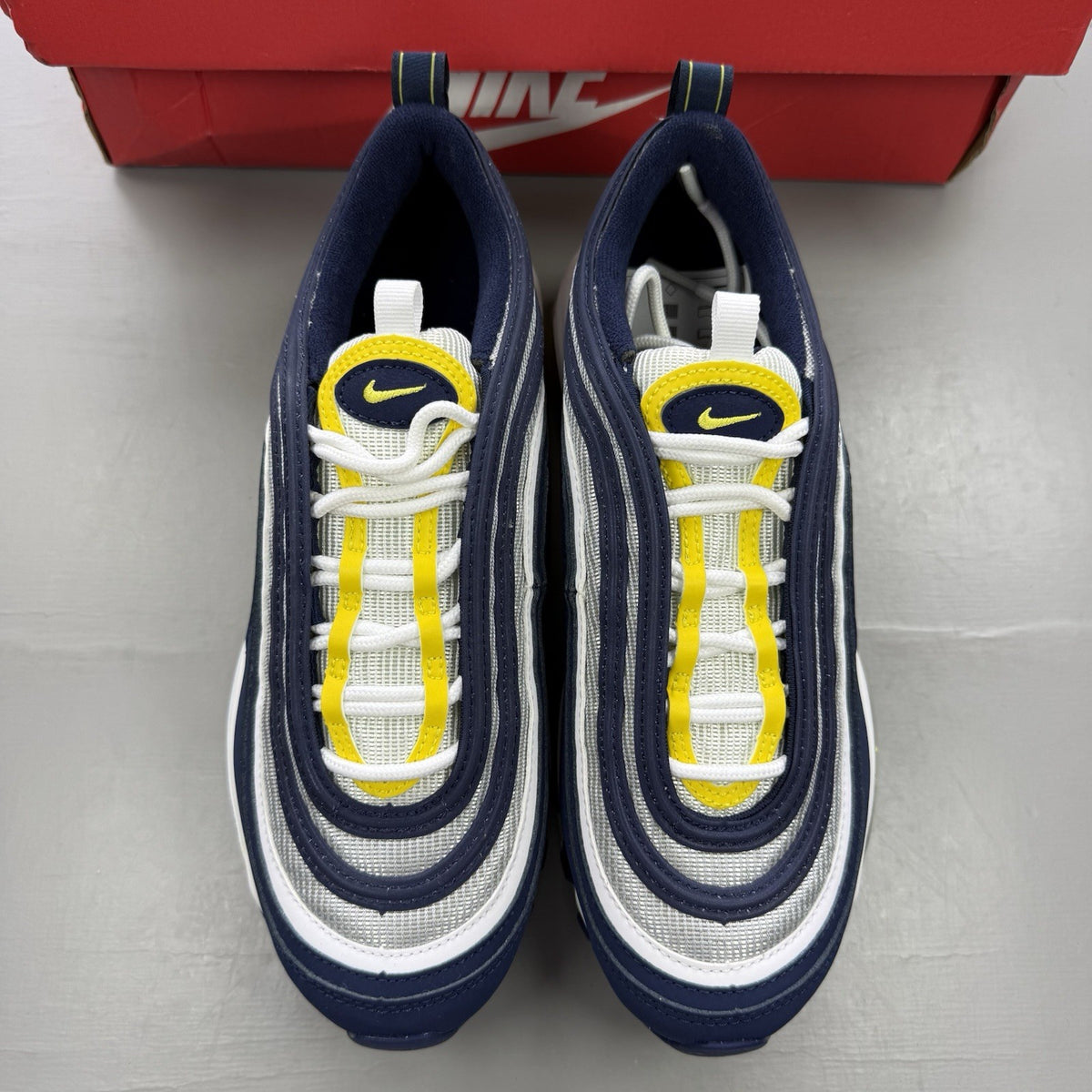 Nike Air Max 97 dark blue trainers with opti yellow and white accents, logo detail.