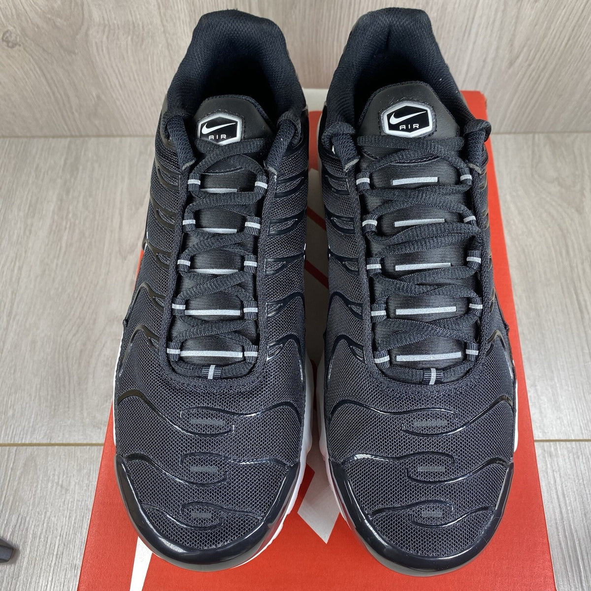 Nike Air Max Plus TN trainers black and white with signature logo and mesh detailing.