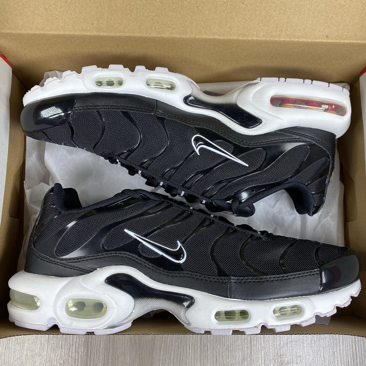 Nike Air Max Plus TN trainers black and white with signature logo and mesh detailing.