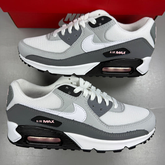 Nike Air Max 90 grey trainers with white and pink accents, featuring logo details.