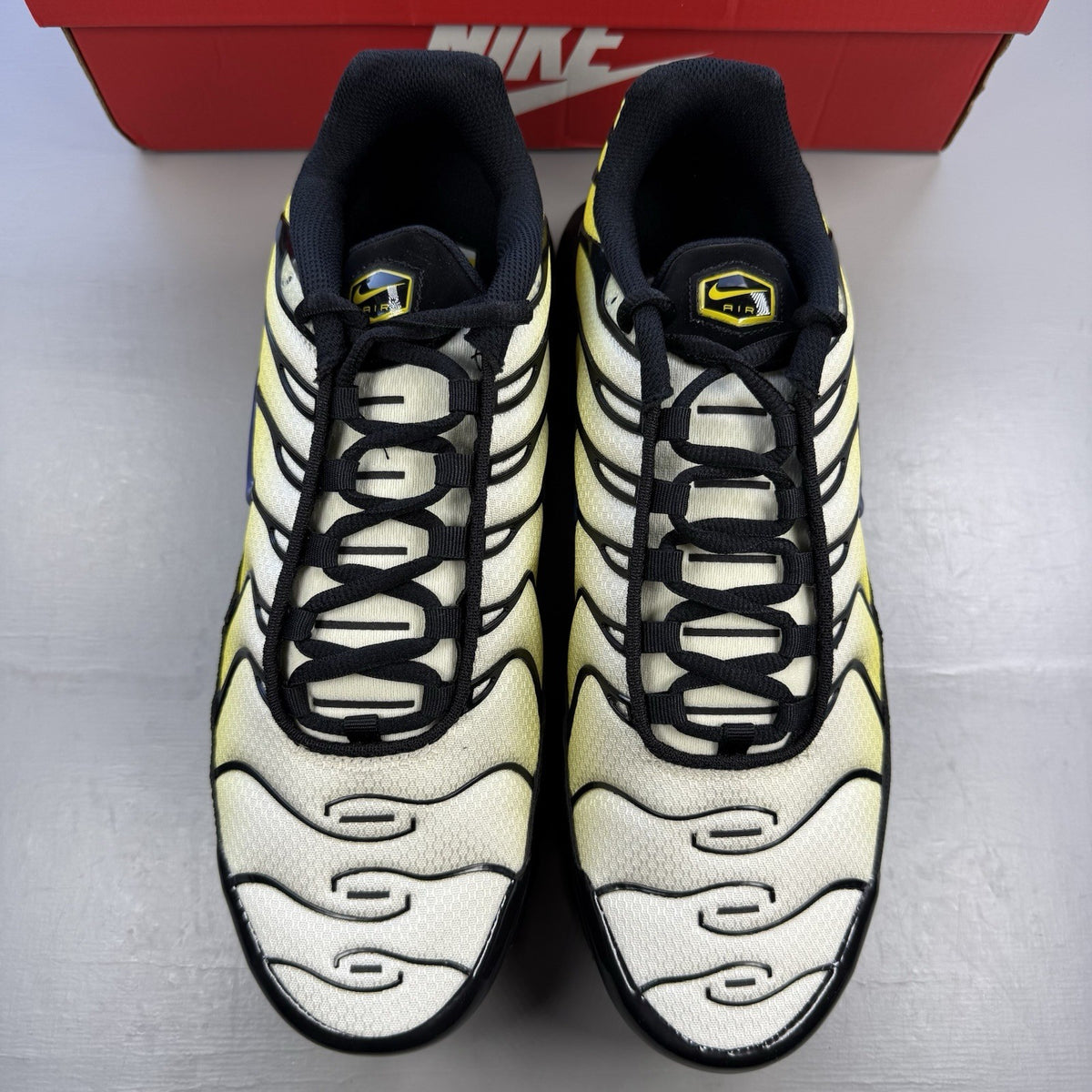 Nike Air Max Plus TN black trainers with bright citron yellow accents and signature logo.