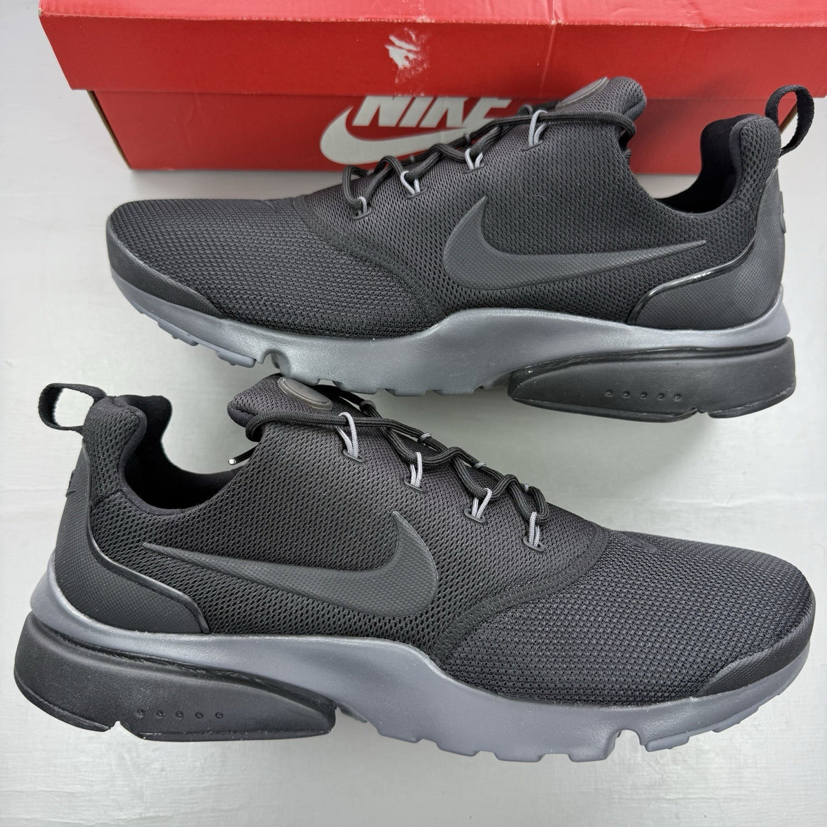 Nike Presto Fly black trainers with dark grey accents and logo detail.
