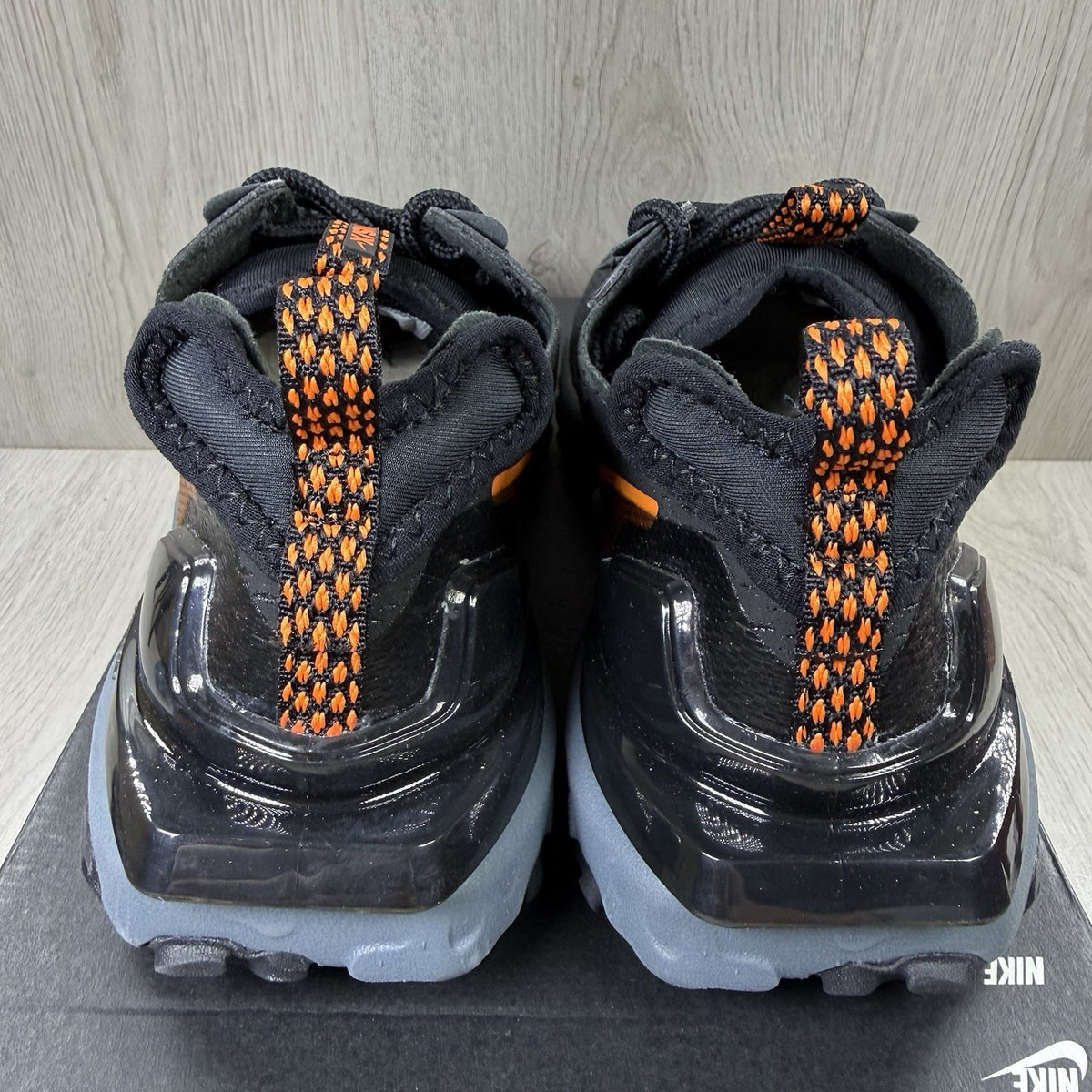 Nike React Vision black trainers with safety orange accents and unique design details.