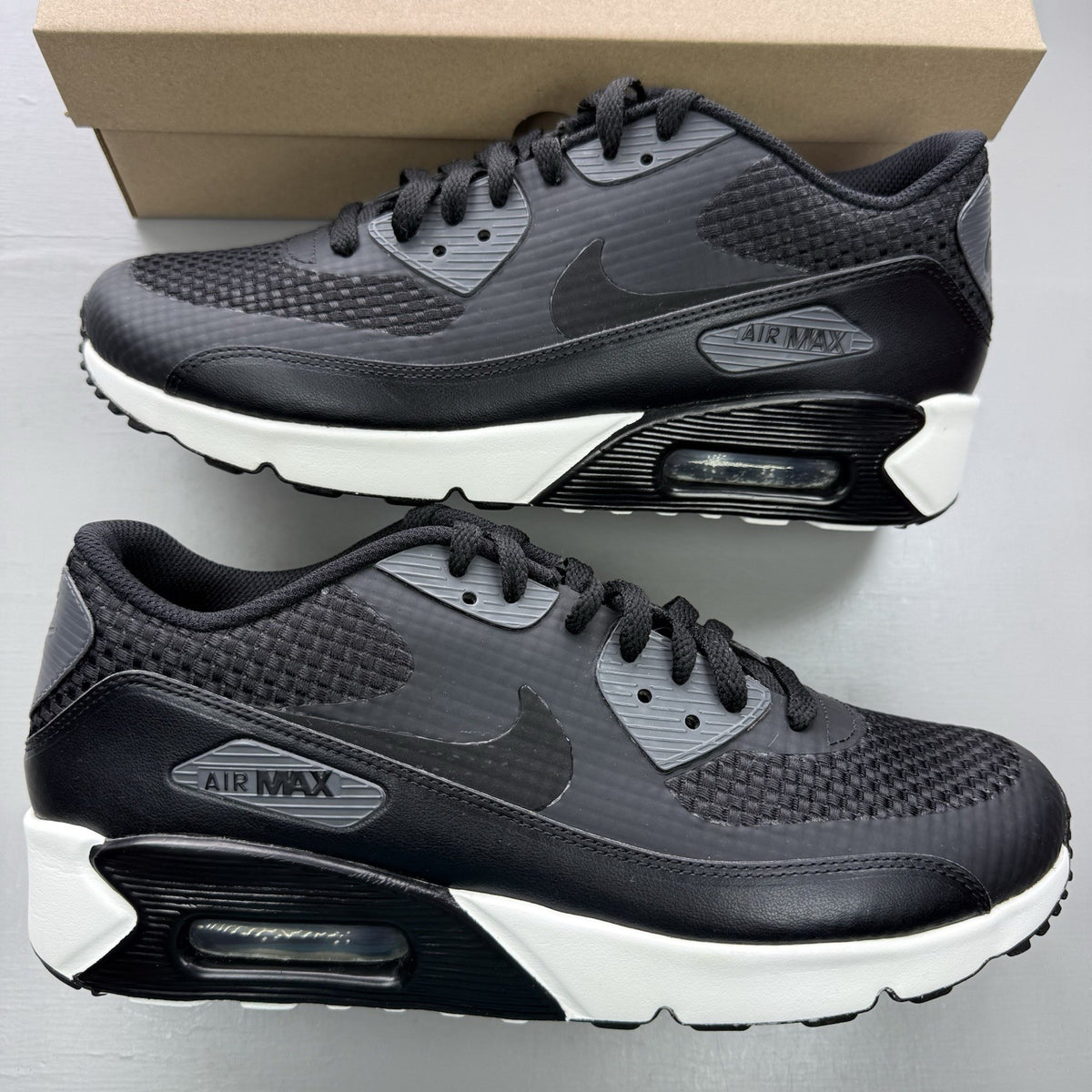 Nike black trainers with dark grey accents and white air bubbles, featuring signature logo.