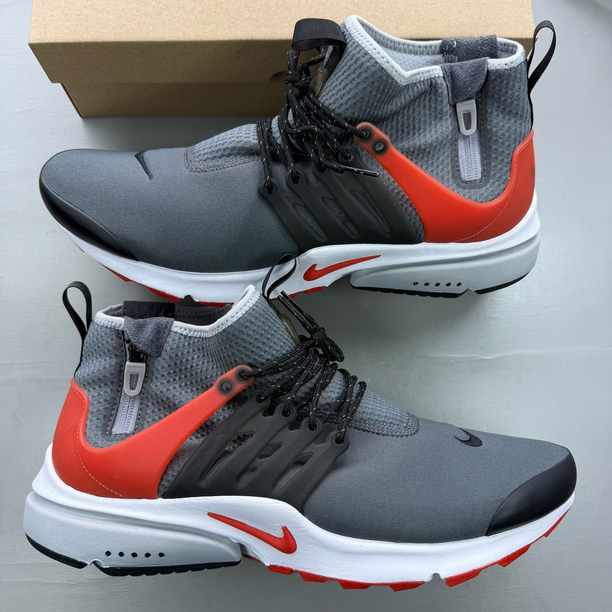 Nike Air Presto grey trainers with black and red accents, featuring a sleek design.