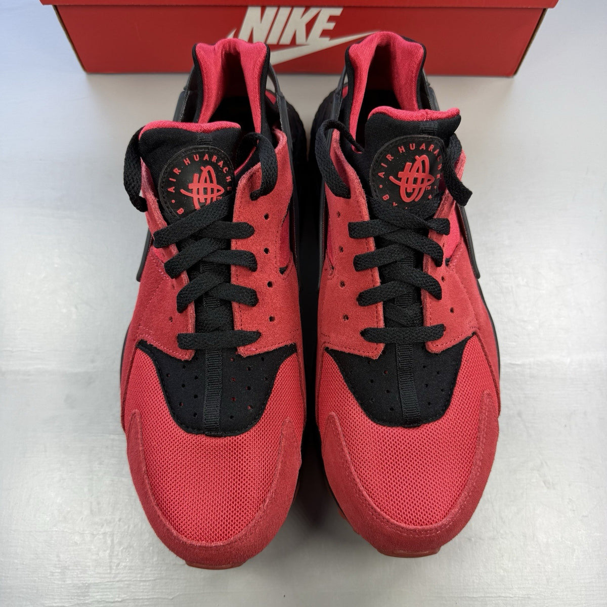 Nike Air Huarache trainers red and black with distinctive logo and unique design details.