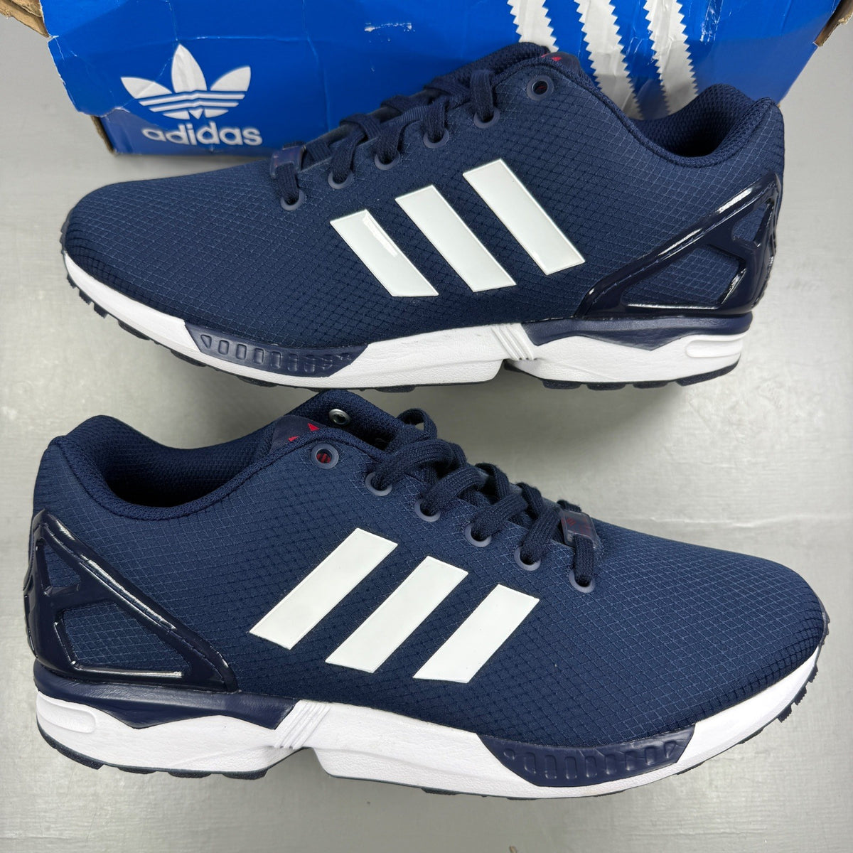 Adidas blue athletic shoes with white accents and ZX Flux logo details.