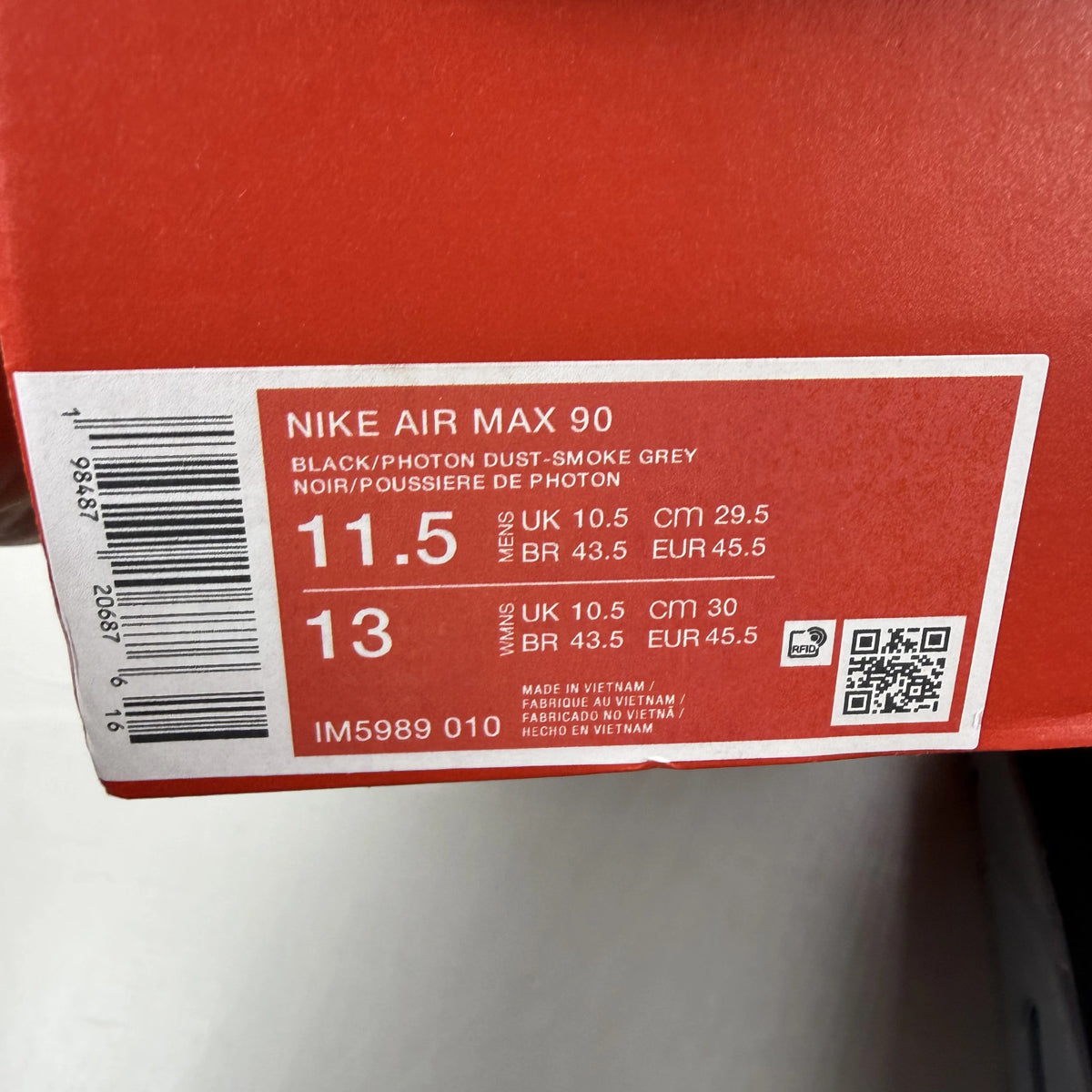 Nike Air Max 90 black trainers with smoke grey accents and logo detail.