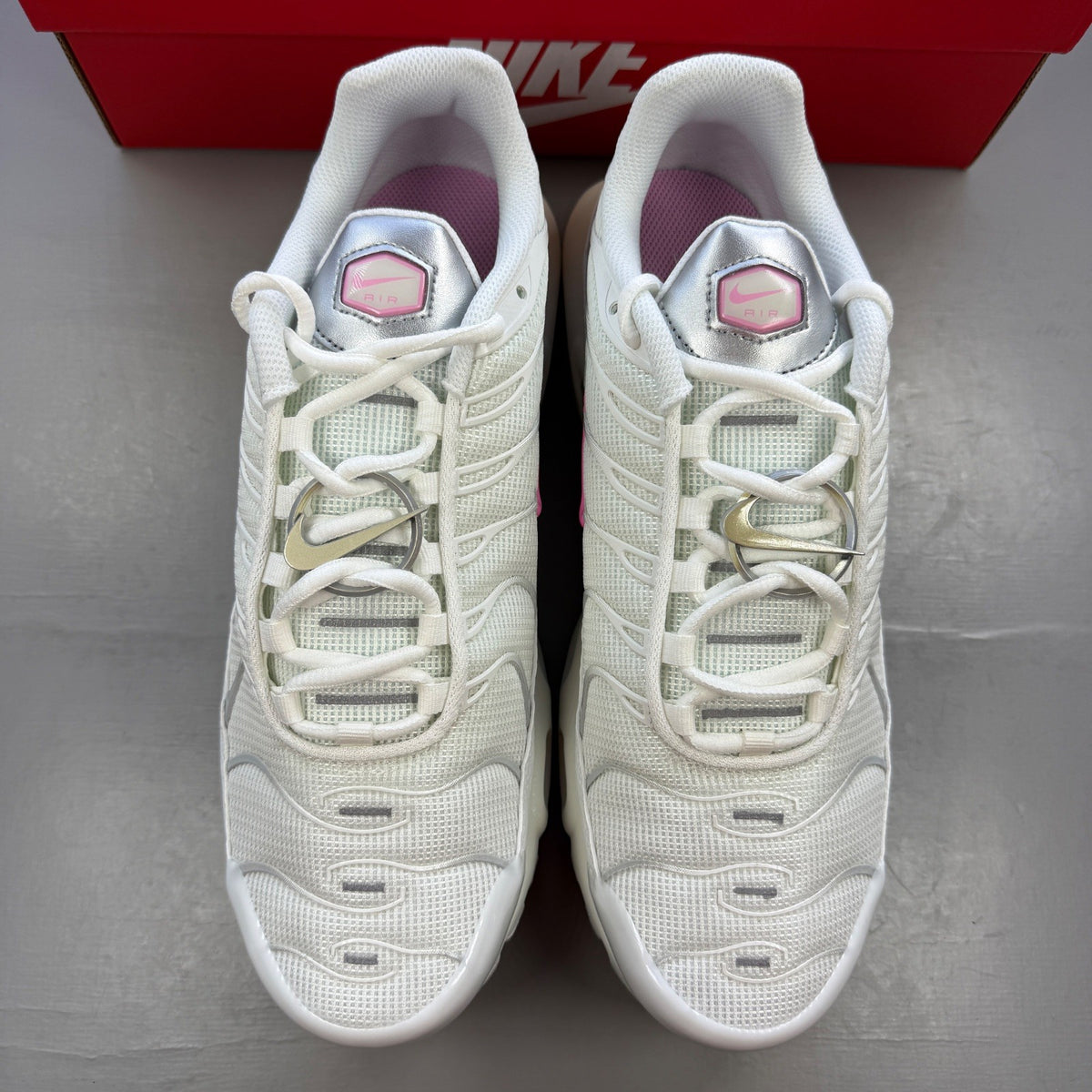 Nike athletic shoes white with pink accents and signature Air Max Plus design.