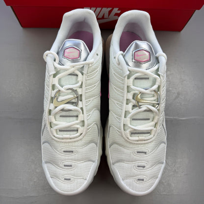 Nike athletic shoes white with pink accents and signature Air Max Plus design.