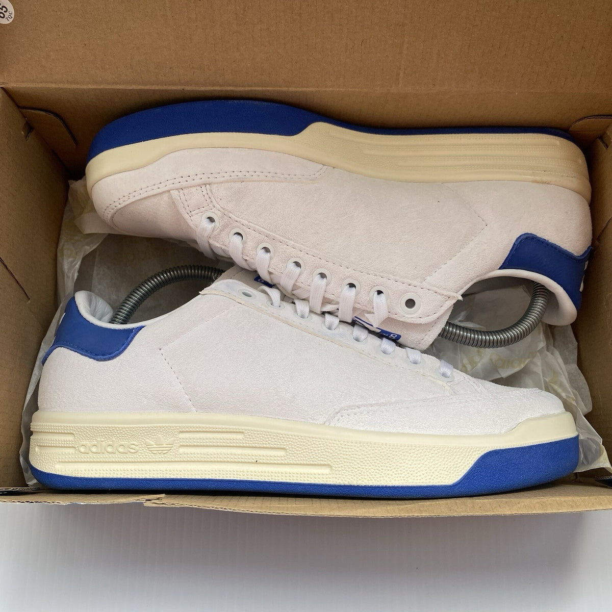 Adidas white trainers with blue and beige accents, featuring classic logo detail.