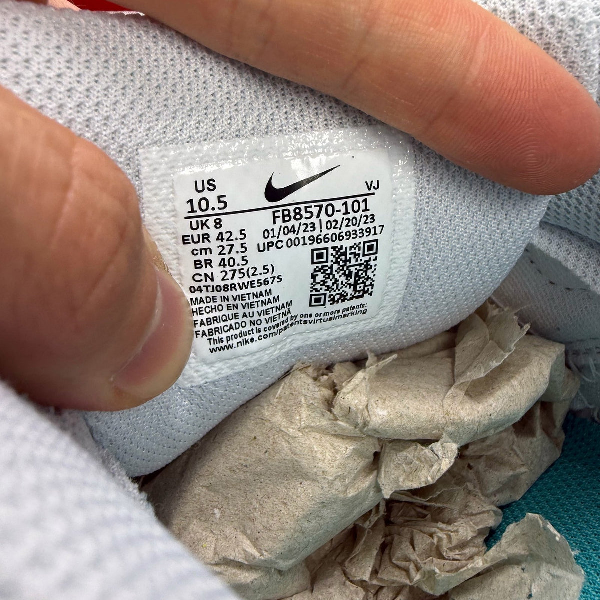 Nike Air Max 90 white trainers with teal accents and visible logo detail.