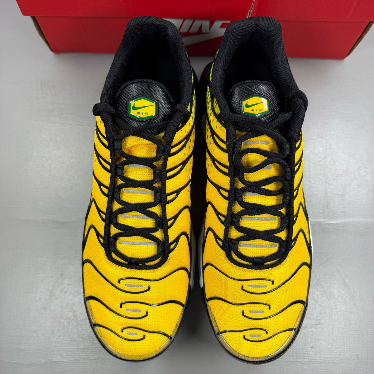 Nike Air Max Plus trainers yellow with pine green accents and logo detail.