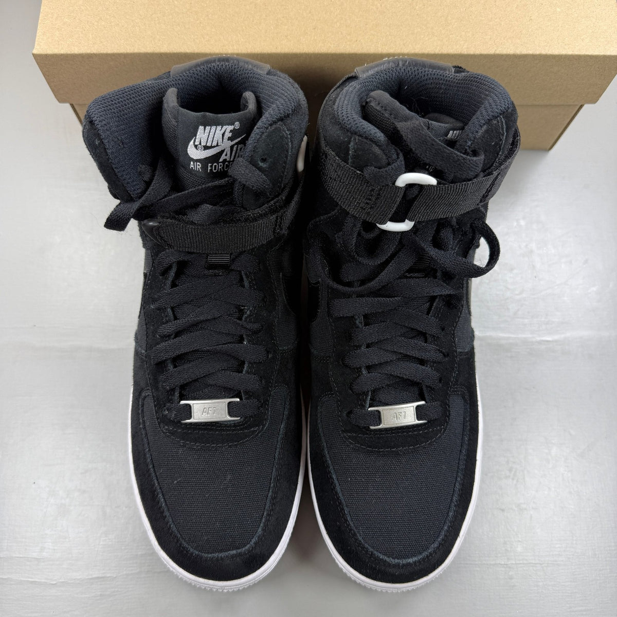 Nike Air Force 1 High black trainers with white logo and durable leather material.