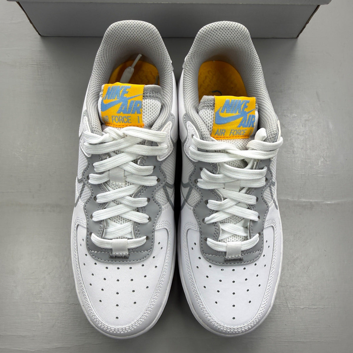 Nike Air Force 1 React white trainers with smoke grey accents and logo details.