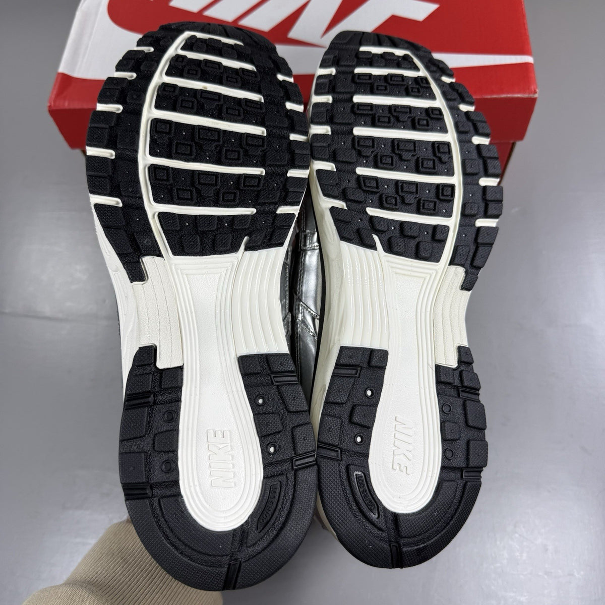 Nike P-6000 metallic silver trainers with black accents and white detailing.