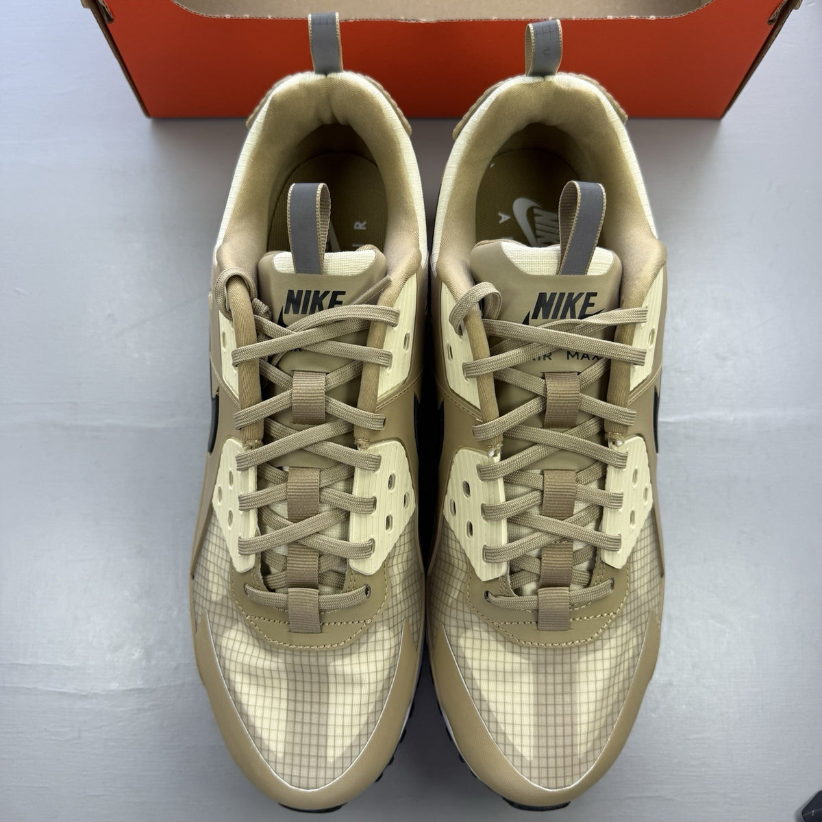 Nike Air Max 90 Drift beige trainers with white accents and logo detailing.