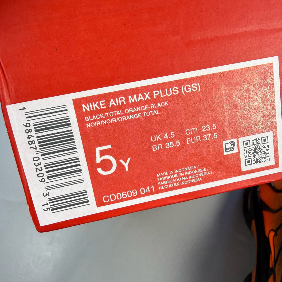 Nike Air Max Plus TN black trainers with orange accents and signature logo details.