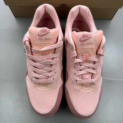Nike Air Max 1 pink trainers with white accents and logo details.
