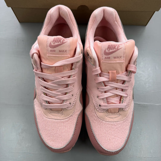 Nike Air Max 1 pink trainers with white accents and logo details.