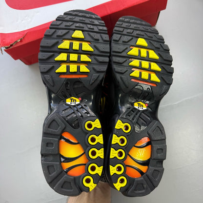 Nike Air Max Plus TN black trainers with signature logo and vibrant sunrise detailing.