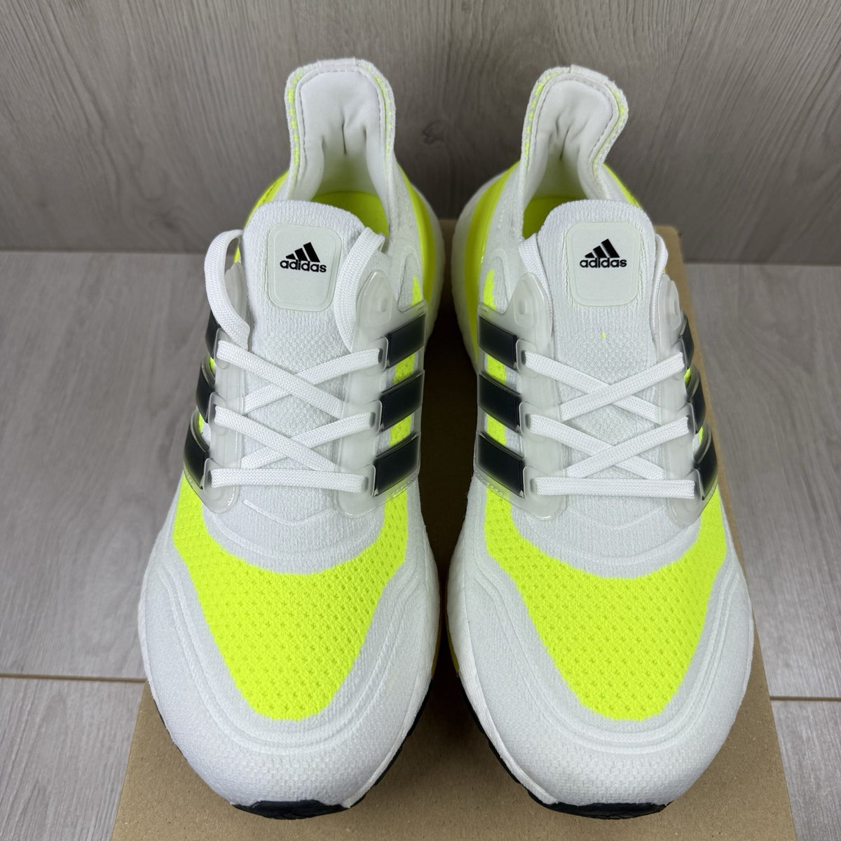 Adidas Ultra Boost 21 white trainers with solar yellow accents and signature three-stripe logo.