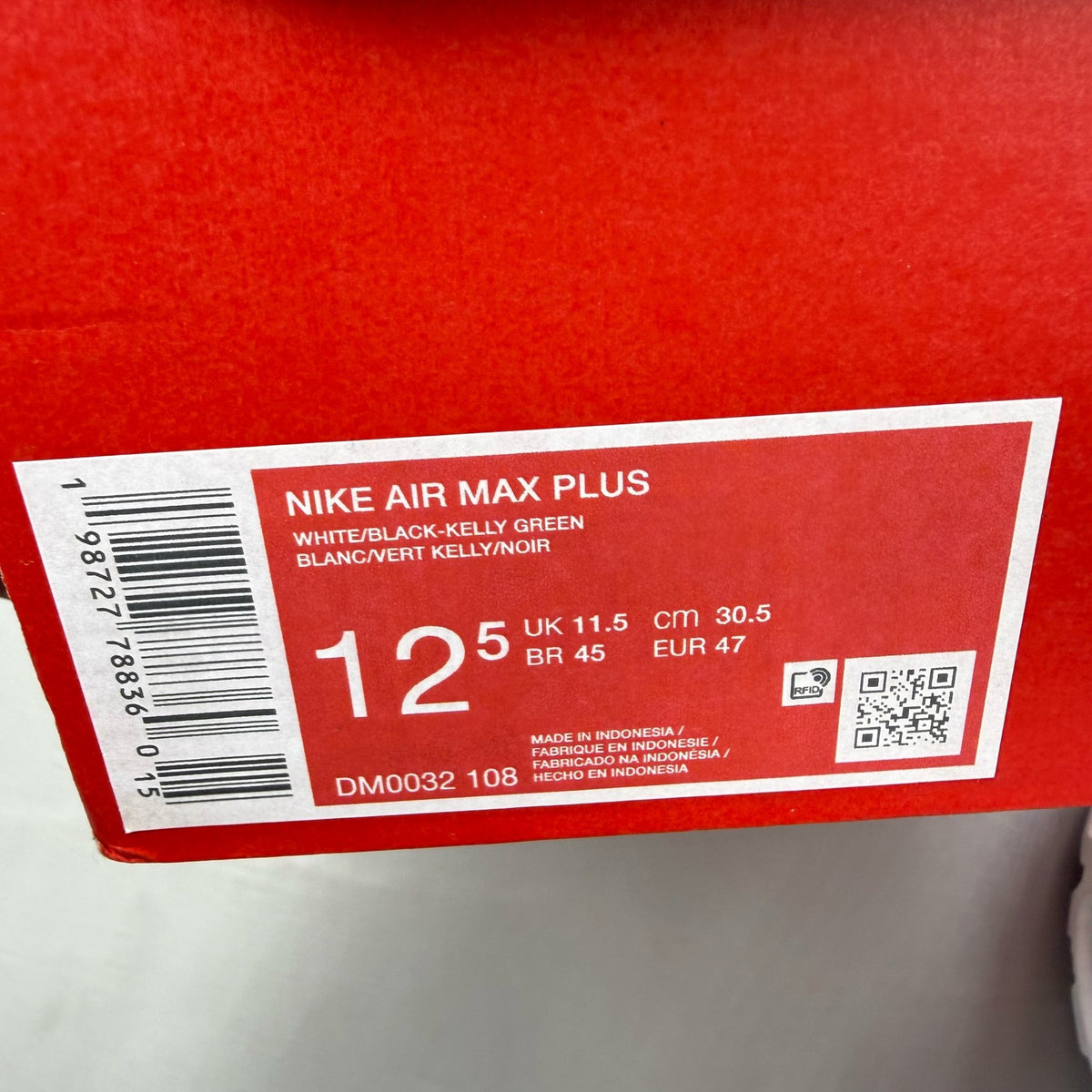 Nike Air Max Plus TN white trainers with green and red accents, featuring iconic logo.