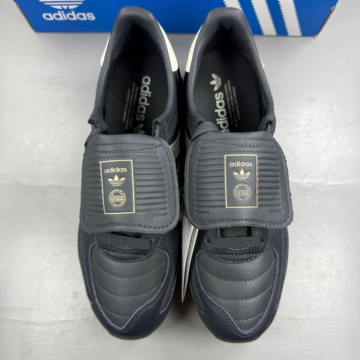 Adidas black deck shoes with blue and white accents, featuring classic logo design.