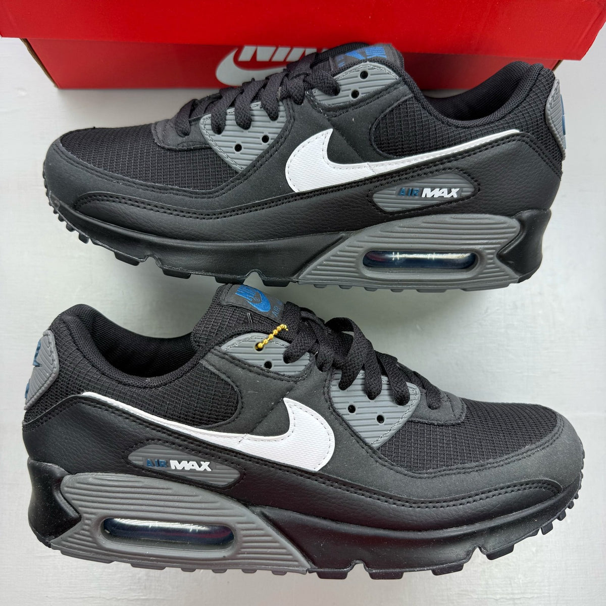 Nike Air Max 90 black trainers with grey accents and logo detail.